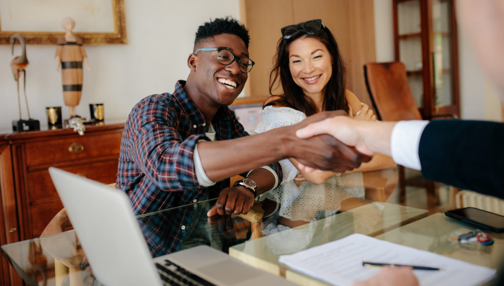 Young couple shaking hands with their lender after getting pre-approved for their home loan.